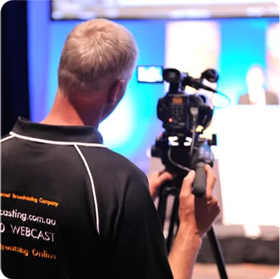 Professional cameraman filming a live event, highlighting custom webcasting services in a high-tech broadcasting environment.