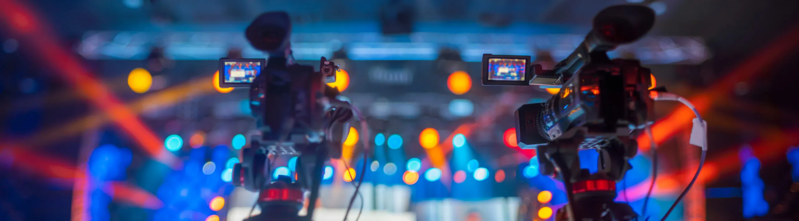 Dual cameras capturing a live concert with bright, colorful stage lighting, highlighting premium event filming and recording services.